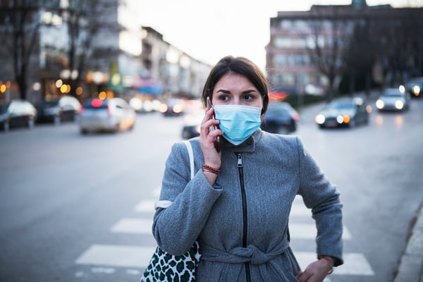 Woman with mask on cellphone- JConnelly blog- How Businesses Can Prepare for Coronavirus